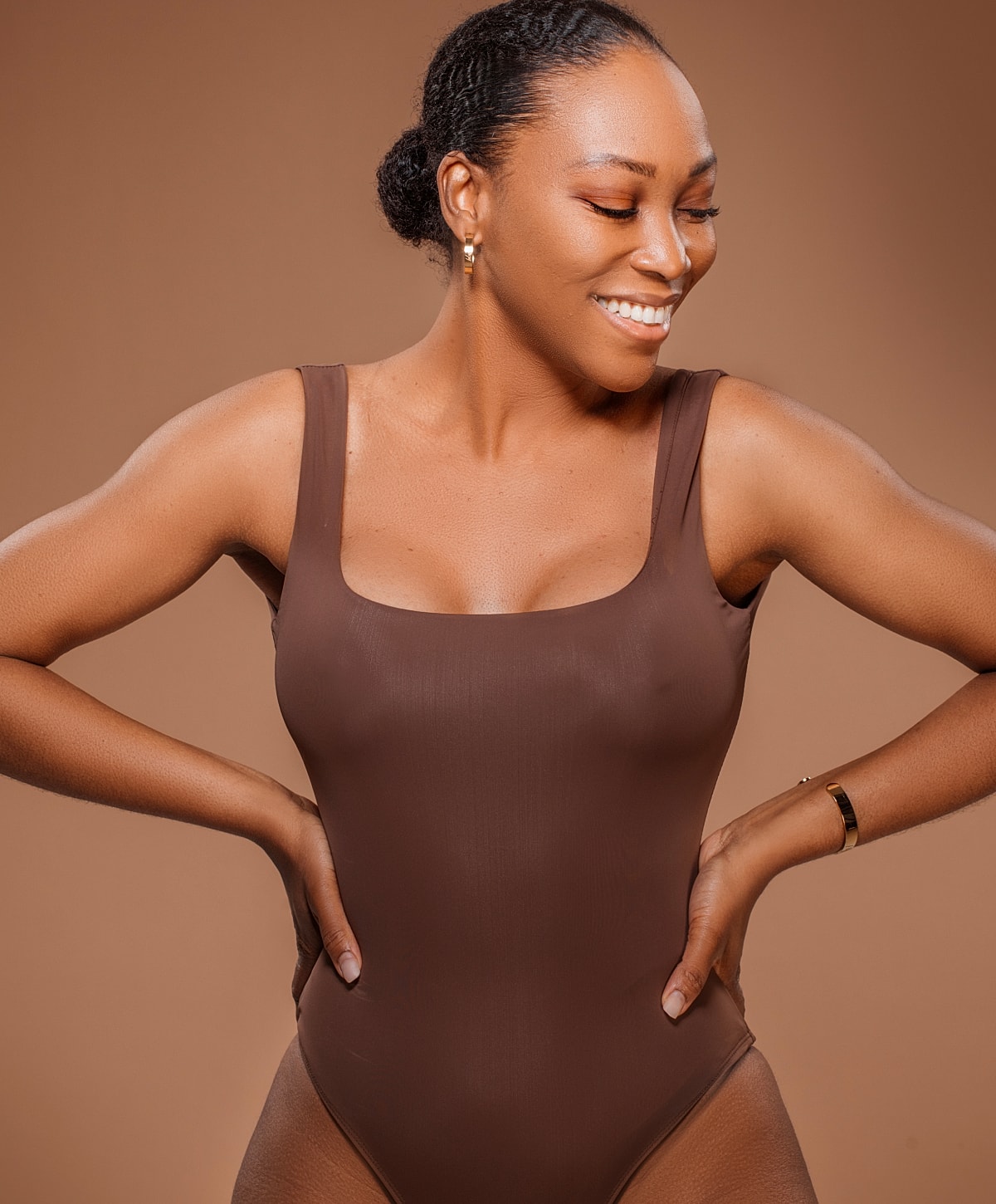 Smiling woman in brown swimsuit, studio background.