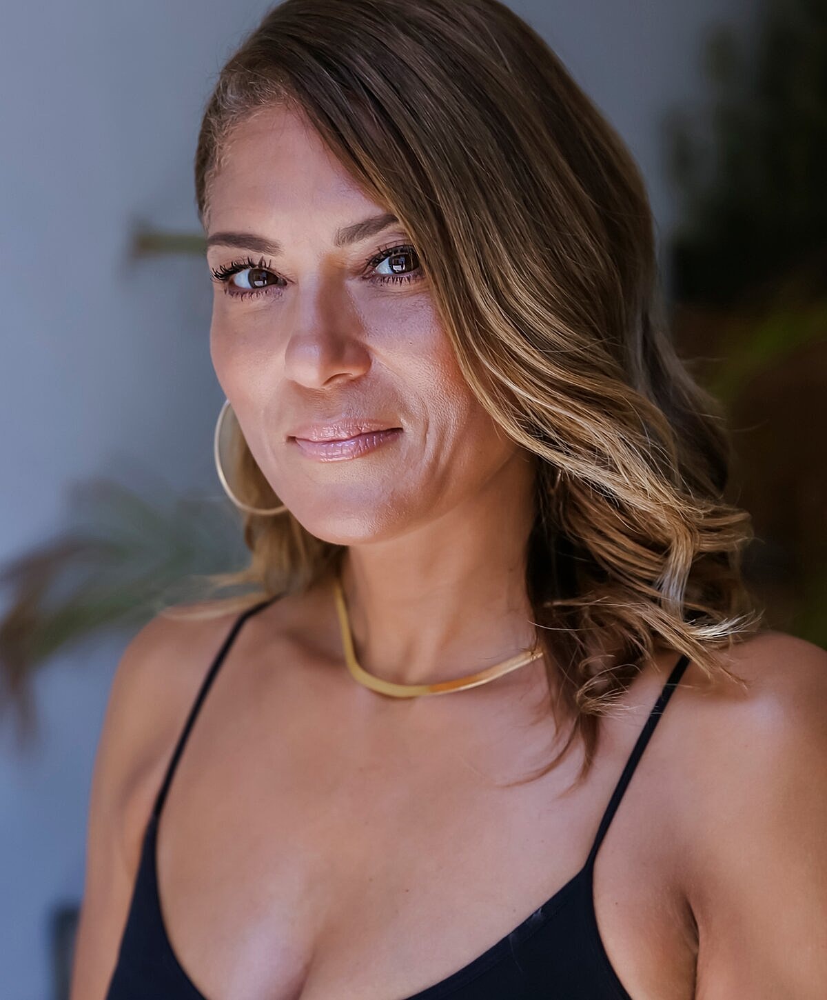 Woman with wavy hair and gold necklace.