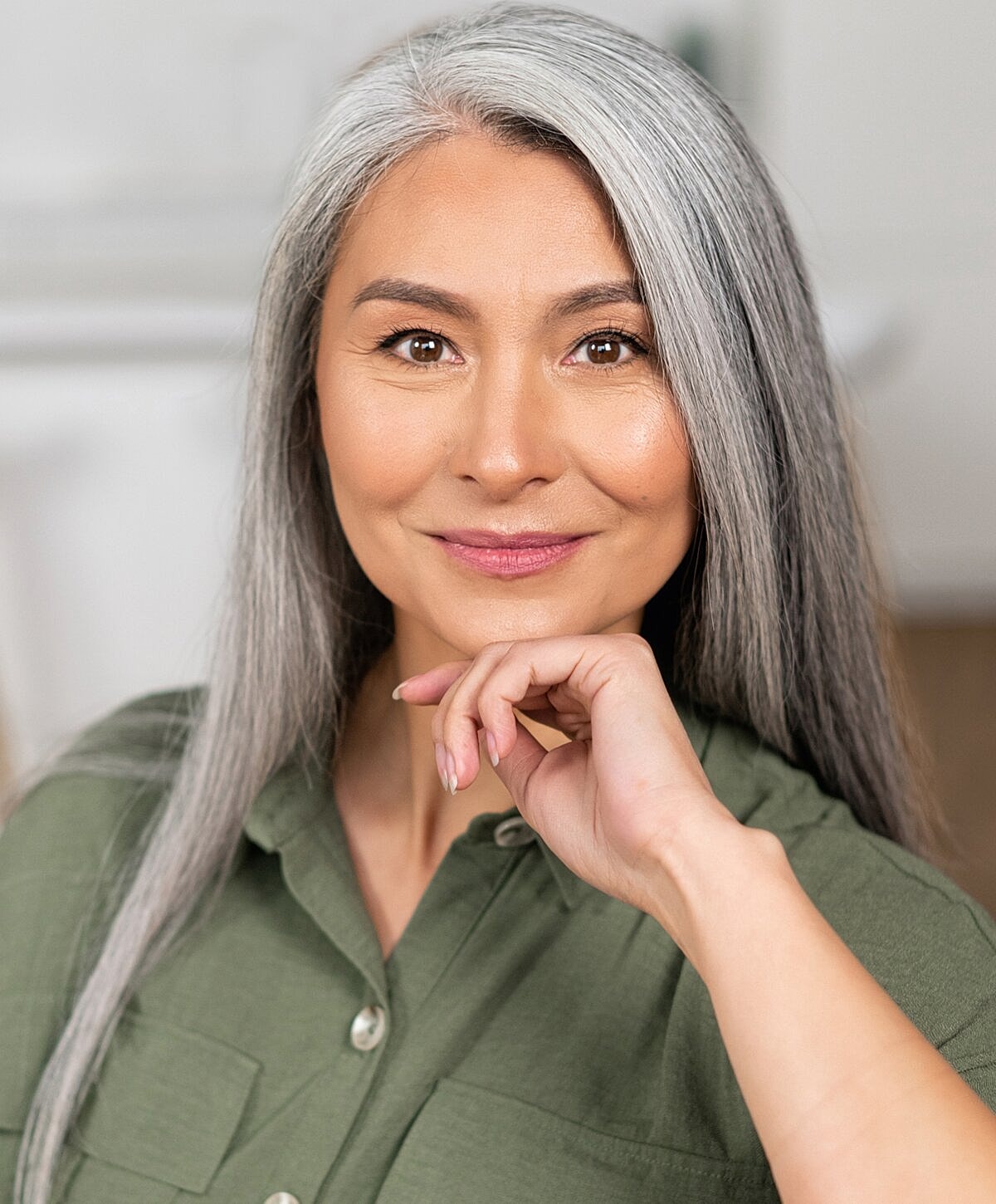 Smiling woman with long, gray hair indoors.