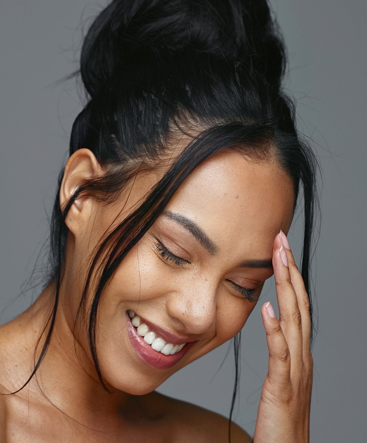 Smiling woman with hand on forehead, joyful moment.