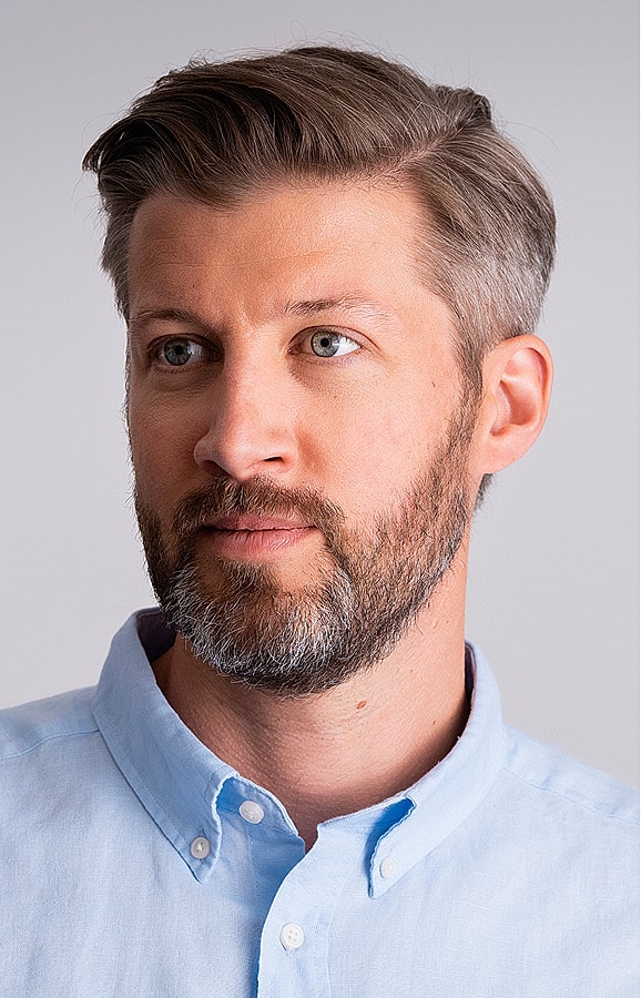 Man with short hair and beard wearing light shirt.