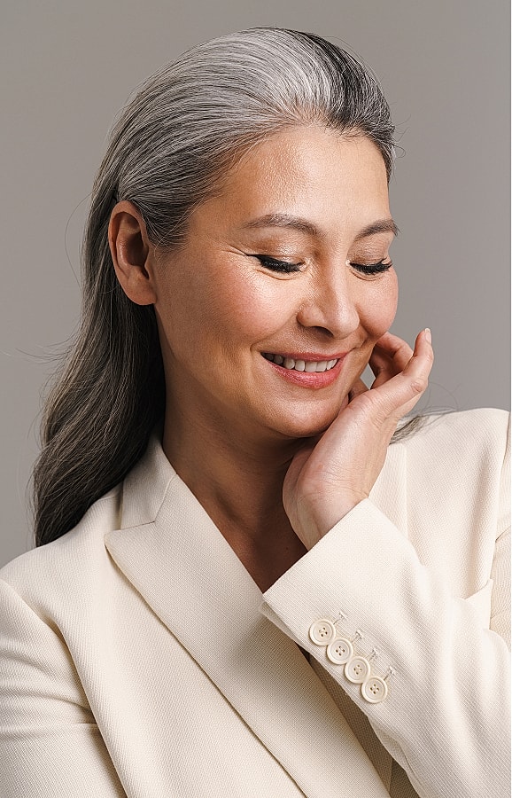 Smiling woman with gray hair in elegant attire.