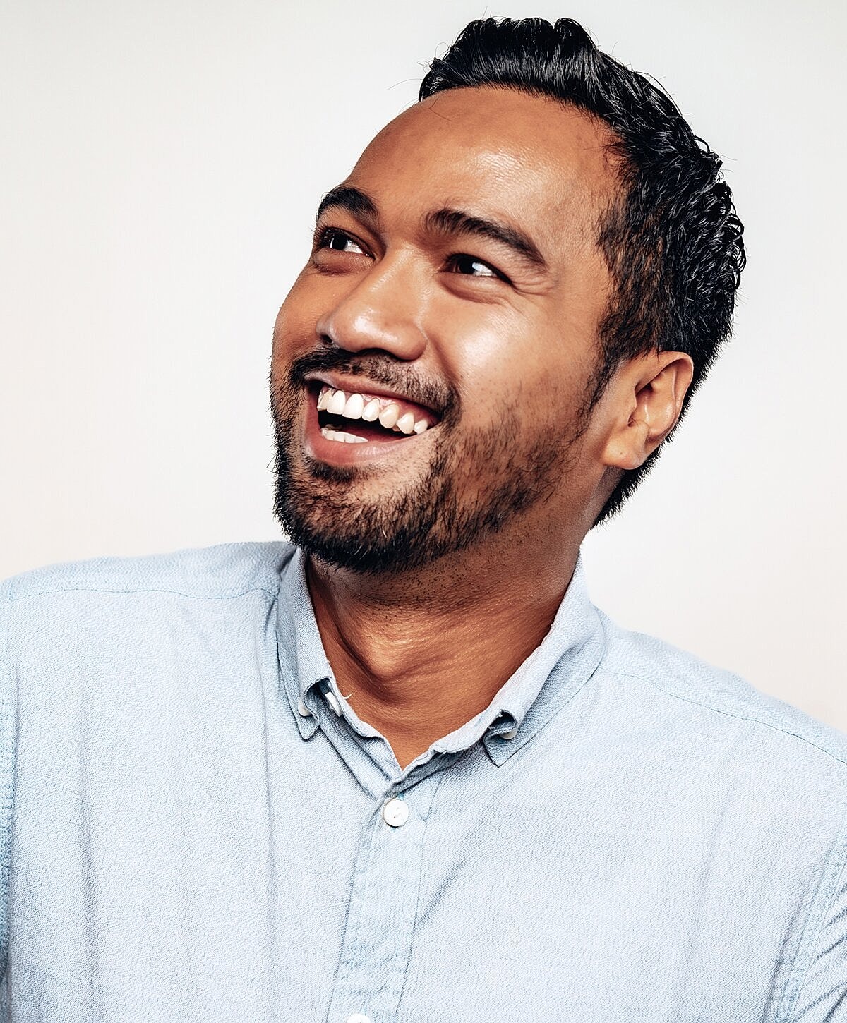 Smiling man in blue shirt against white background.