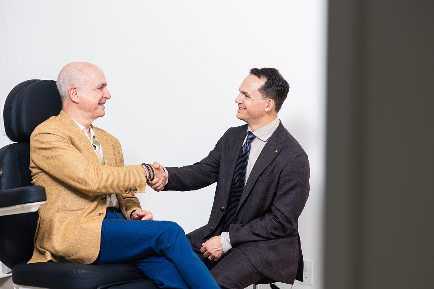 Two men shaking hands in an office setting.