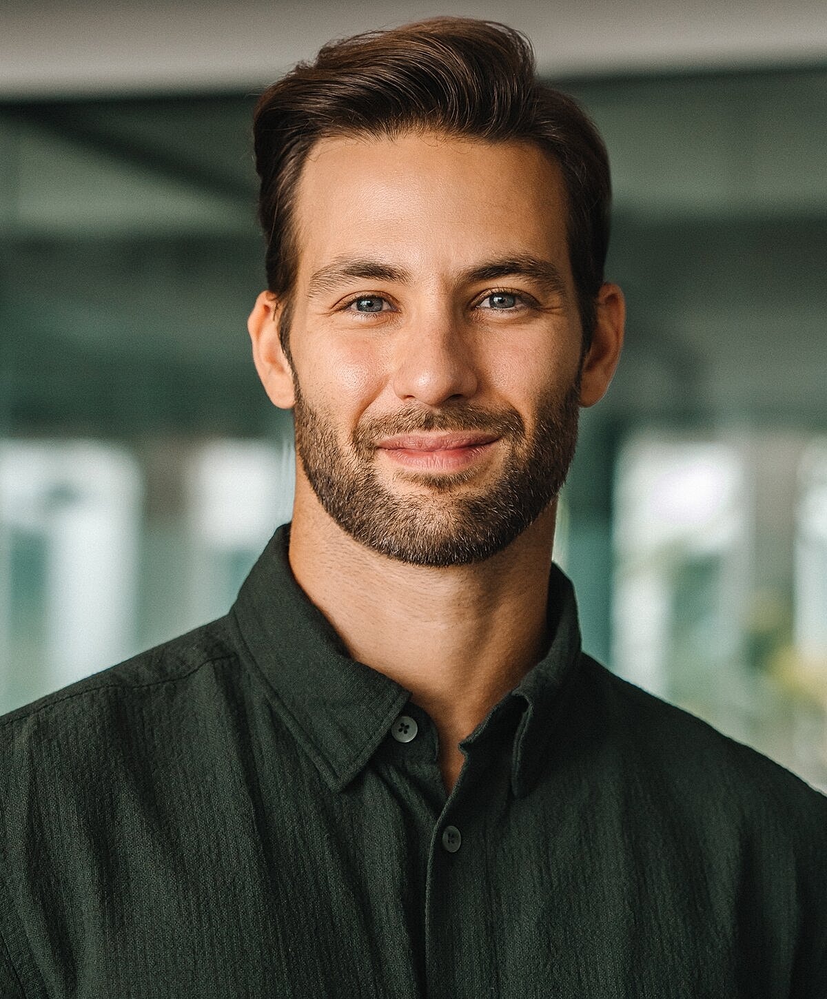 Smiling man in green shirt, indoors.