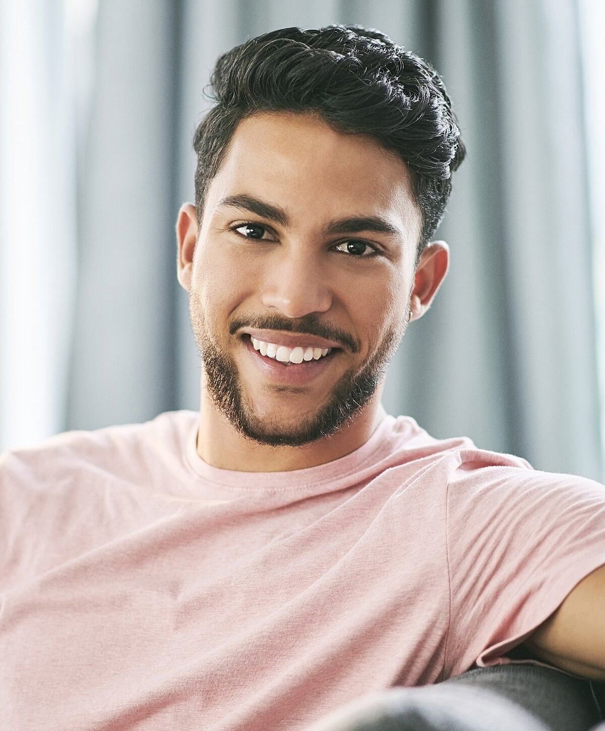 Smiling man in a pink shirt at home.