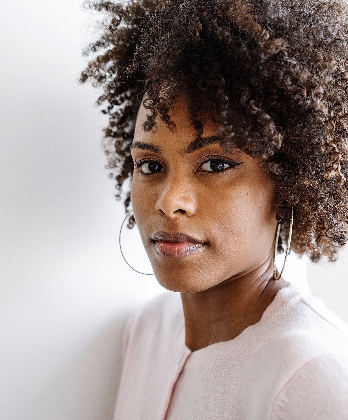 Woman with curly hair and hoop earrings.