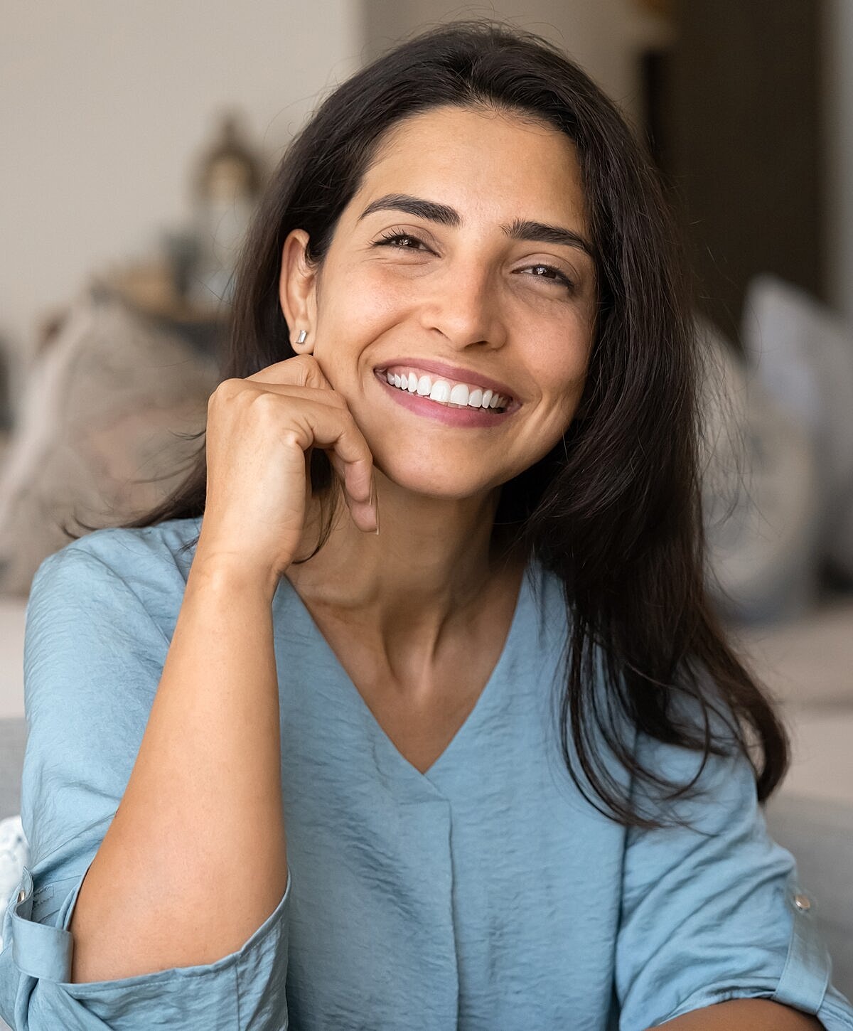 Smiling woman in light blue shirt indoors.