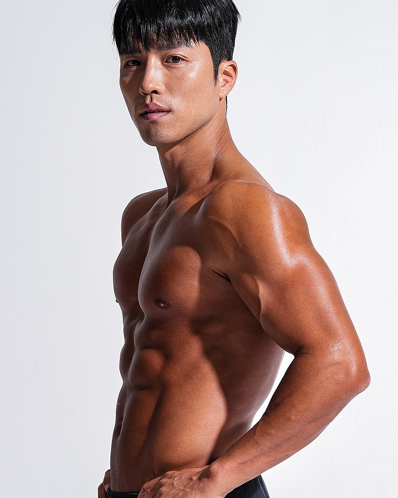 Athletic man posing confidently against neutral background.