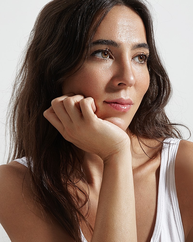 Woman resting her chin on hand, thoughtful expression.