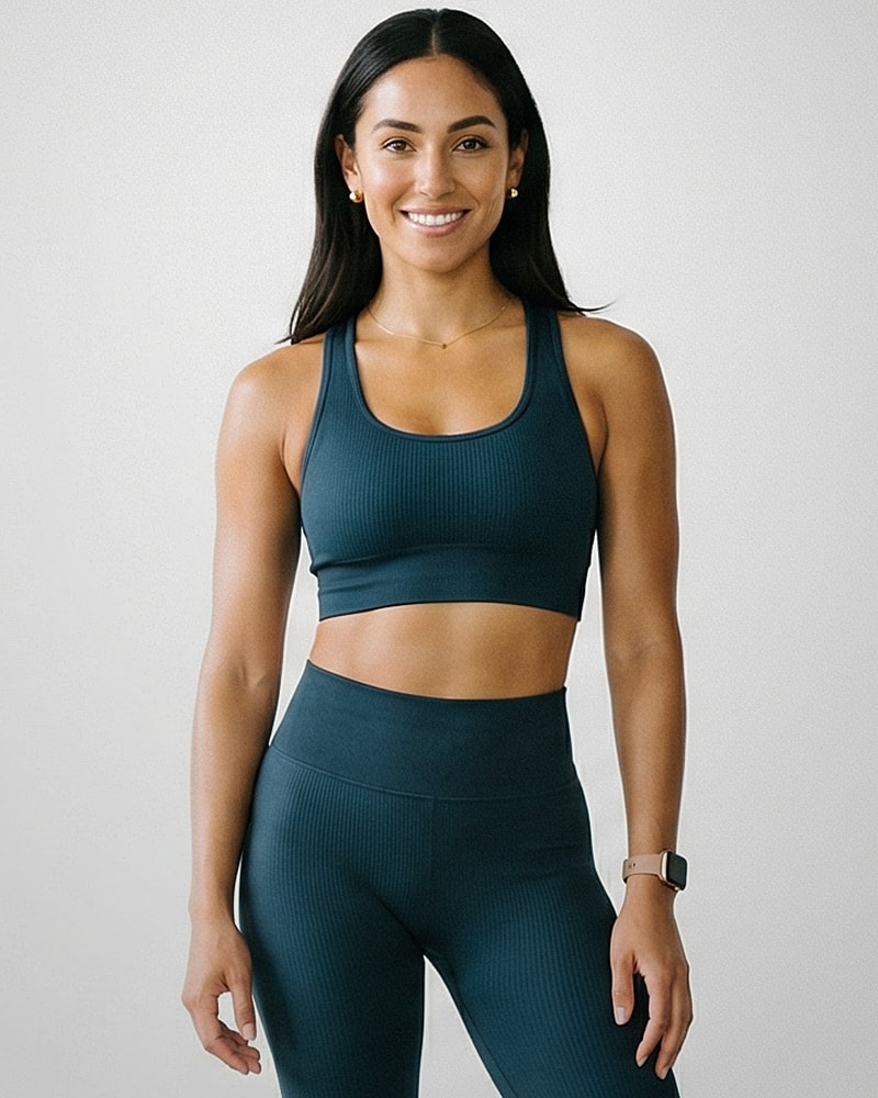 Smiling woman in athletic wear against neutral background.