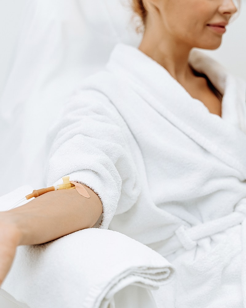 Woman in robe receiving intravenous treatment.