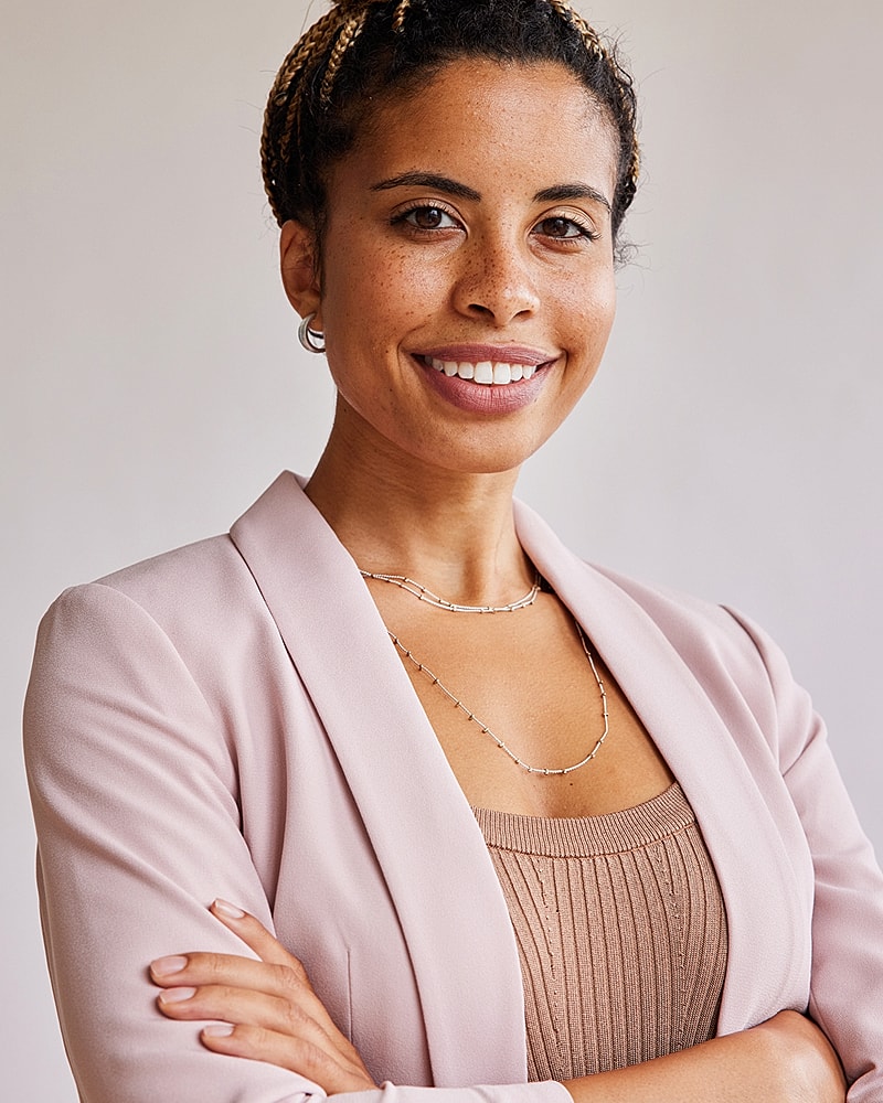 Smiling woman in professional attire with arms crossed.
