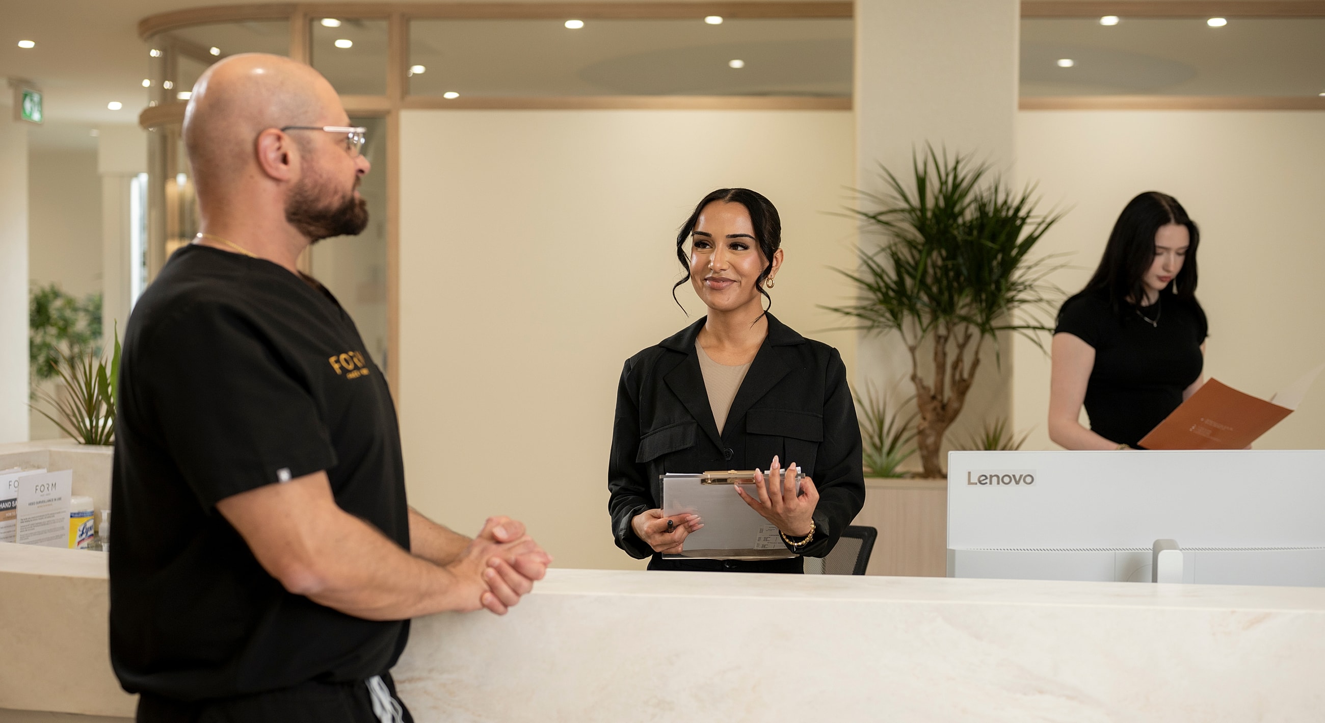 Receptionist assisting a client in a modern office.