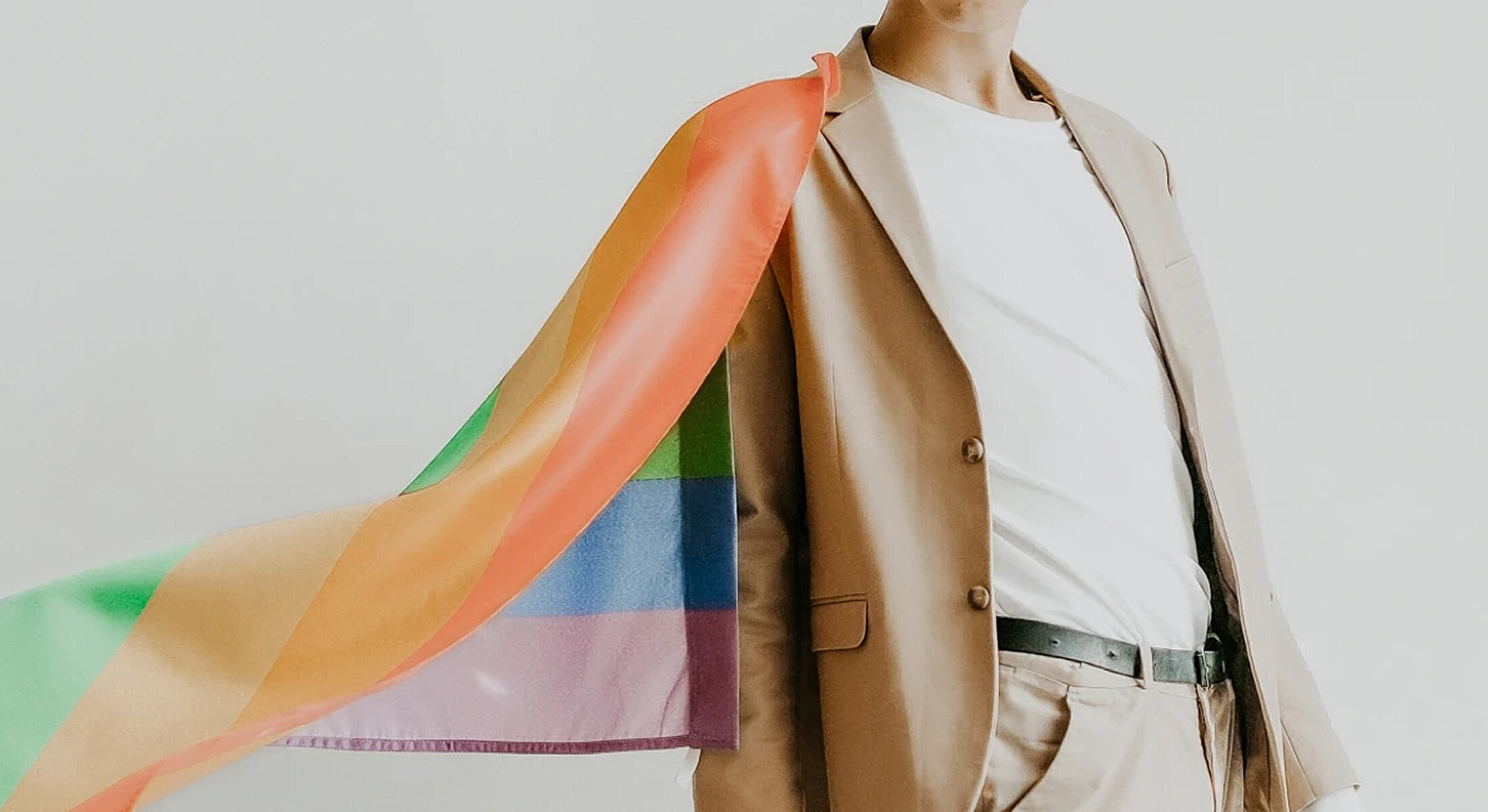 Person in suit with rainbow flag cape.