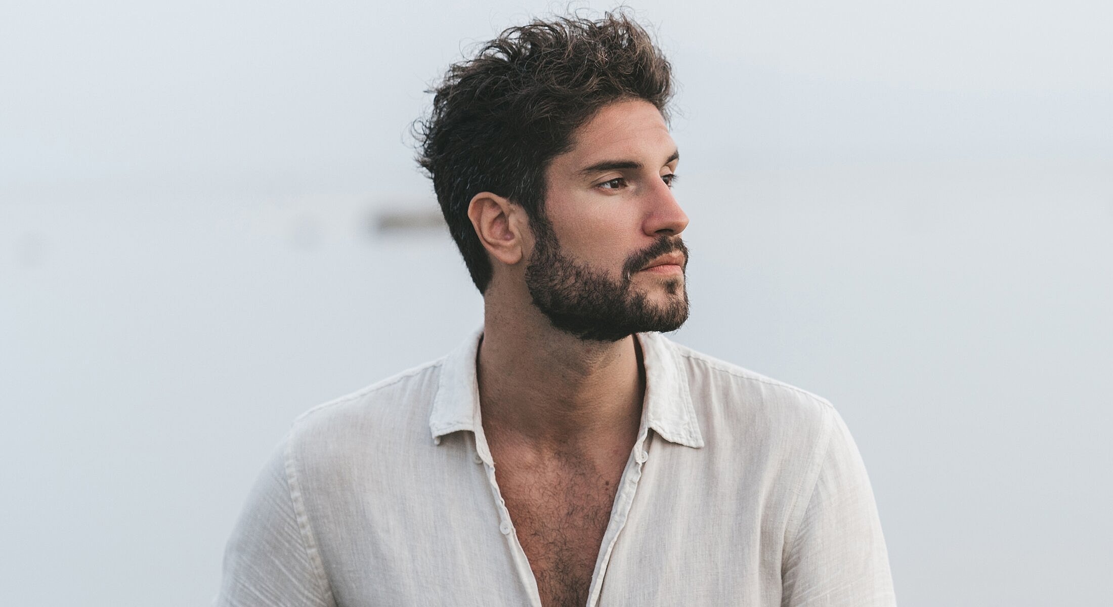 Man with beard looking thoughtfully into the distance.