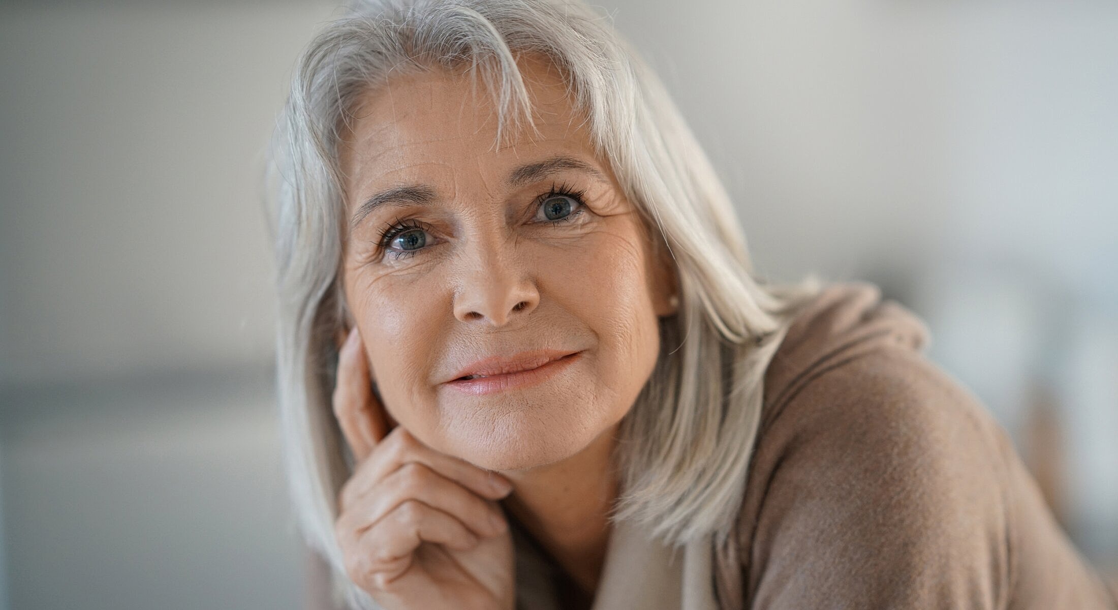 Smiling older woman with gray hair and thoughtful expression.