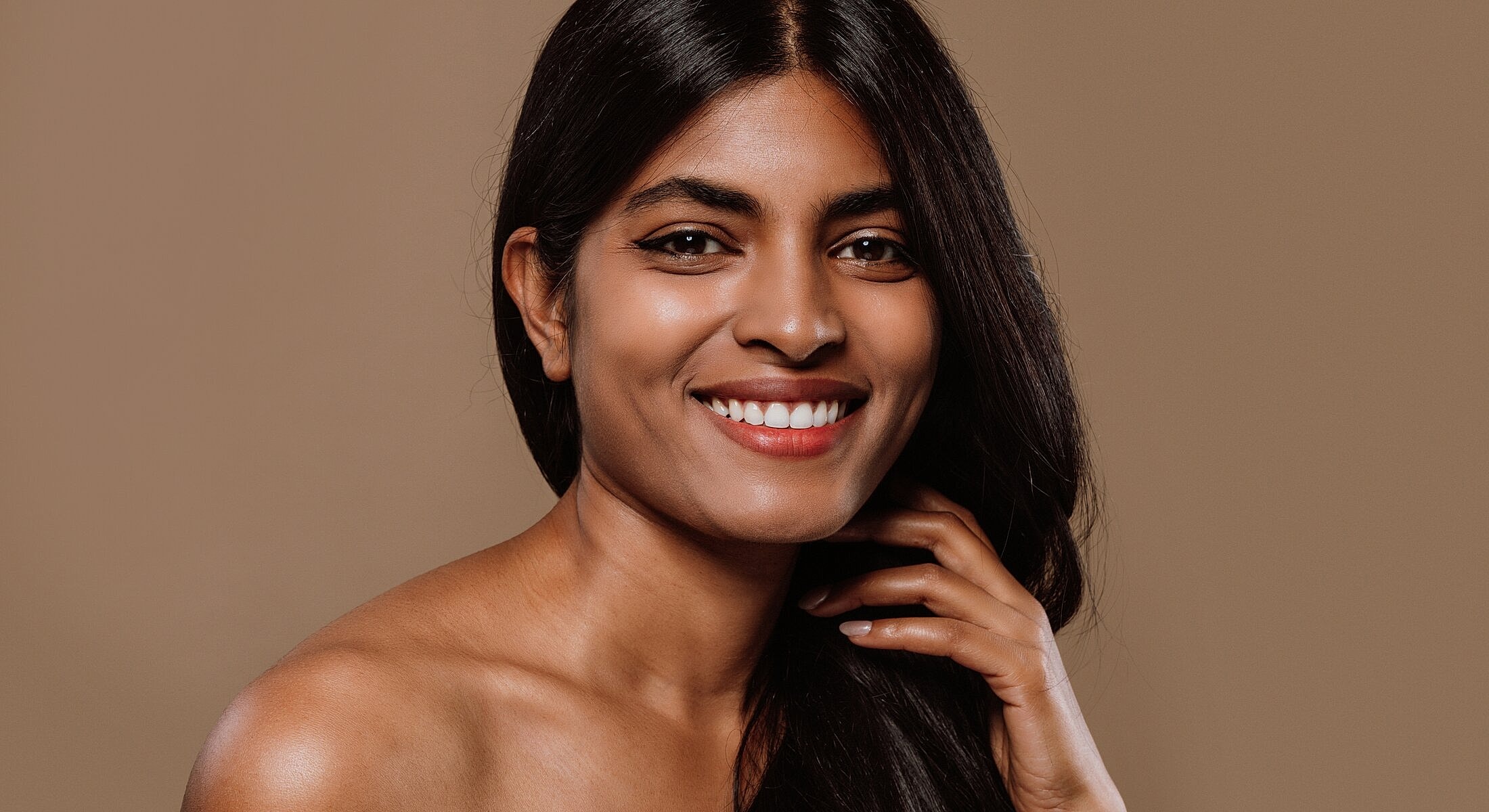 Smiling woman with long dark hair against background.