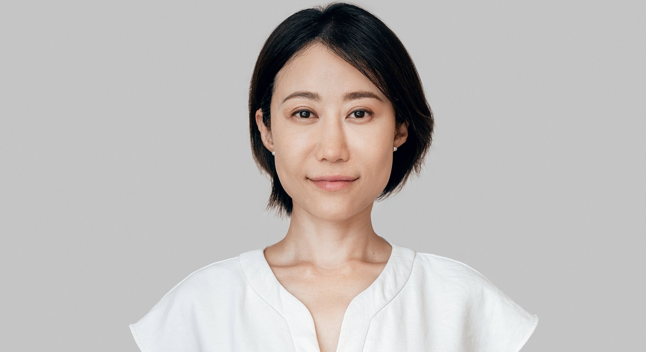 Person with short hair wearing a white top.