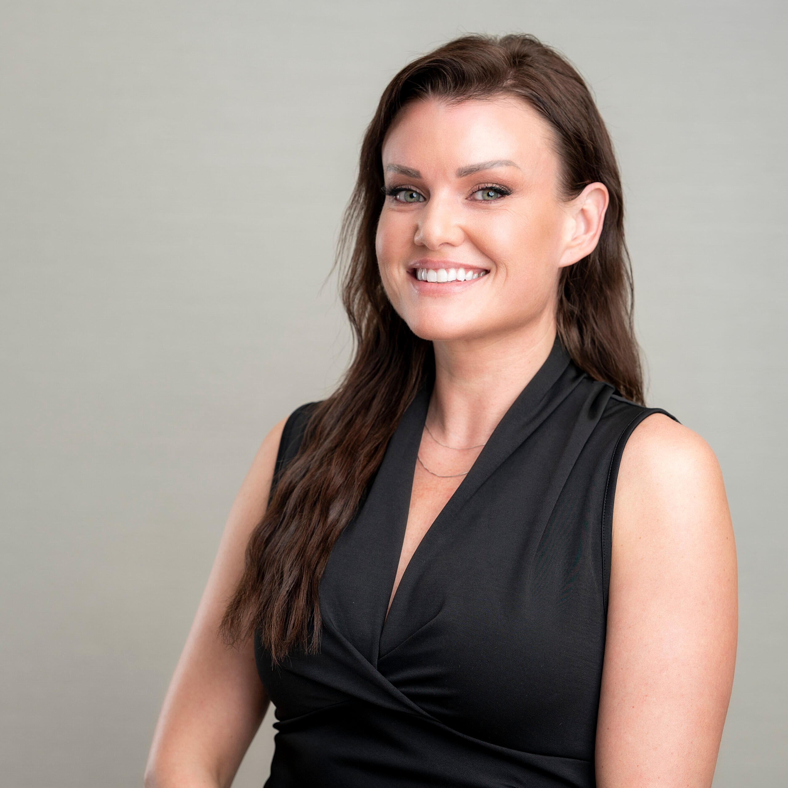 Smiling woman in a black sleeveless top.