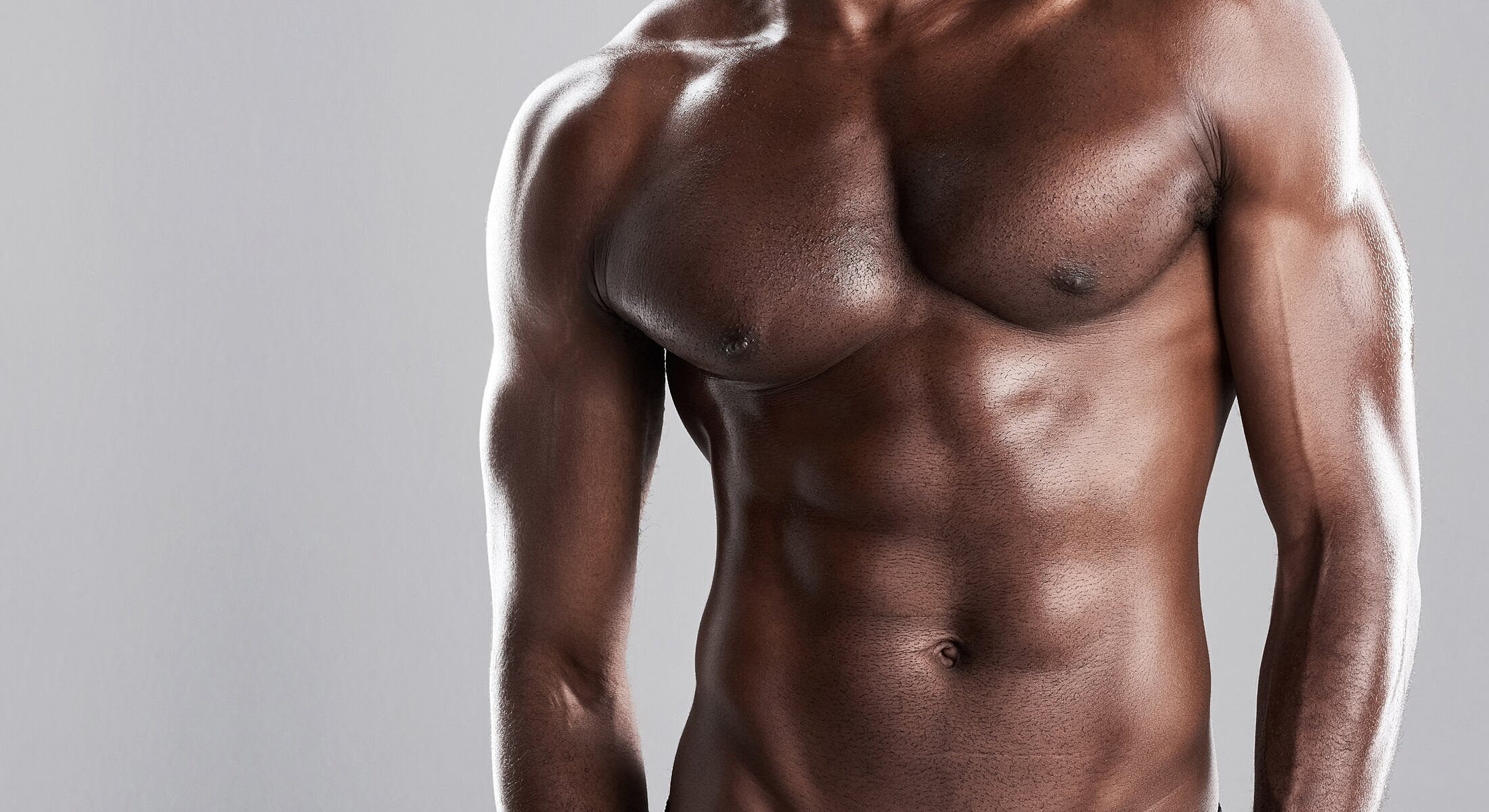 Muscular male torso against gray background.
